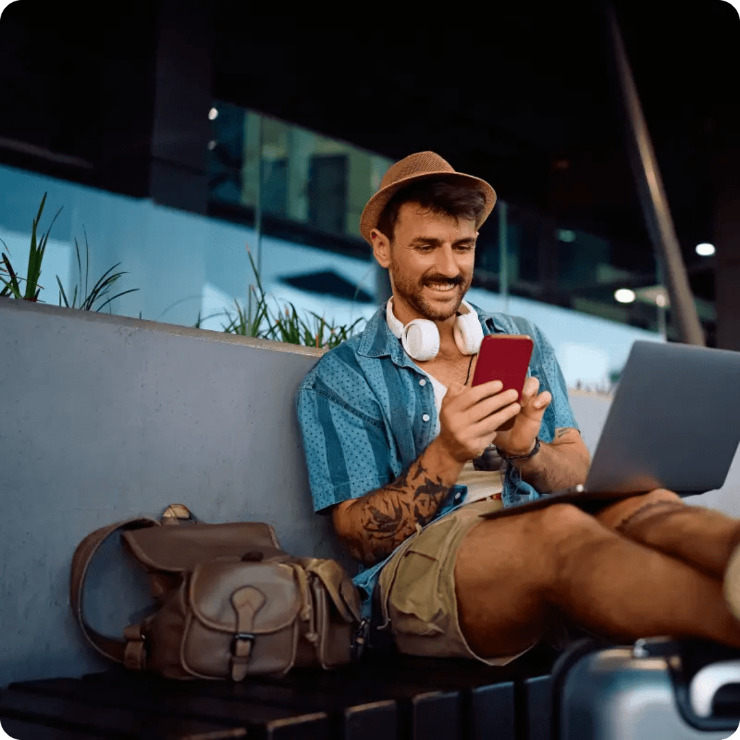 Happy traveler using laptop and phone